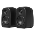 Kanto Audio UKI desktop speakers with 100W power, Bluetooth connectivity, black active bookshelf speakers on a desk.